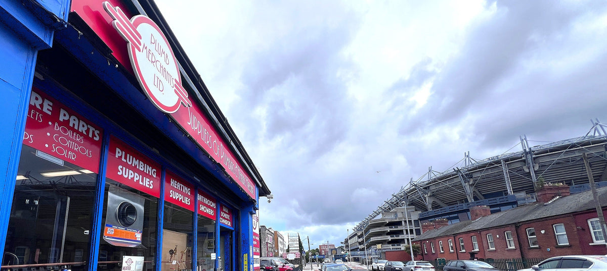 Building exterior with a sign for plumbing supplies and Croke Park stadium in the background.